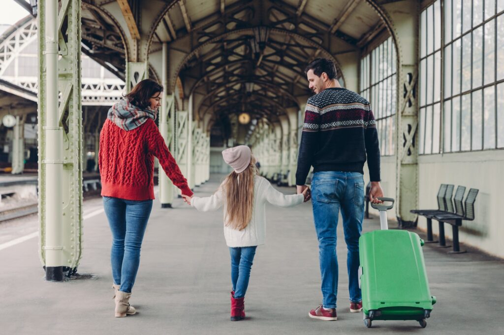 Affectionate parents and their daughter keep hands together, going to have trip abroad