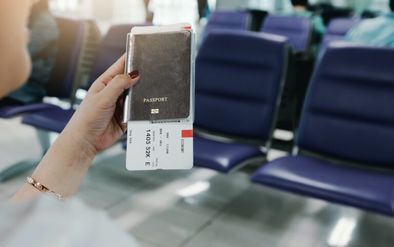 Woman hand holding passport and flight ticket in airport.